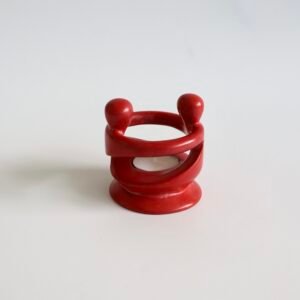 Rode speksteen kandelaar met abstract sculptuurontwerp, twee bolvormige handvatten en spiraalvormige lichaamsvorm.