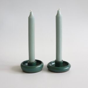 Twee groene aardewerk kandelaars met ronde voet en witte kaarsen, vintage setje.