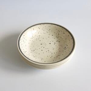Set van vier vintage pastaborden van Eit England in roomwit met zwarte spikkels en een dunne zwarte rand.