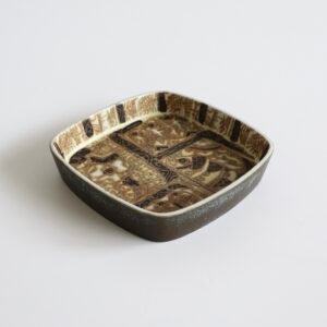 Vintage Royal Copenhagen fajance schaal met vierkante vorm, bruin-beige glazuur en decoratief patroon met figuren en ornamenten in midcentury stijl.