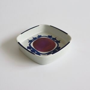 Vintage Royal Copenhagen fajance schaal met vierkante vorm, wit glazuur en blauw decoratief patroon met rood cirkelcentrum.