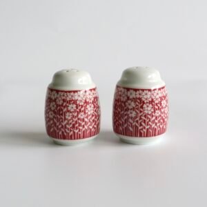 Vintage peper- en zoutstel in rood-wit porselein met bloemetjes- en takjespatroon, twee identieke potjes met witte deksels.