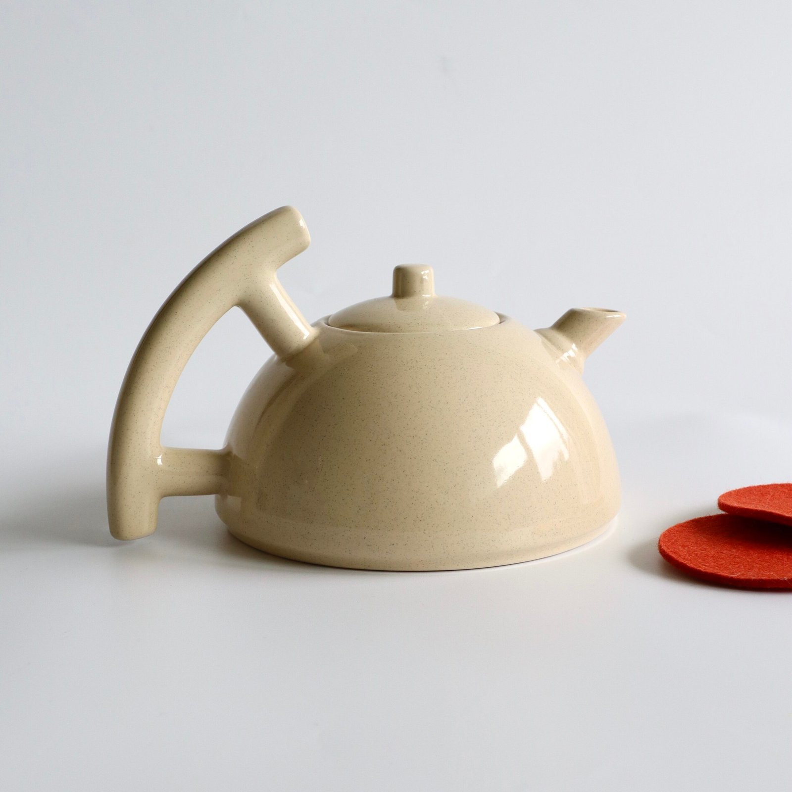 Vintage keramieke theepot in beige met spikkeljes, gebogen handvat en deksel.