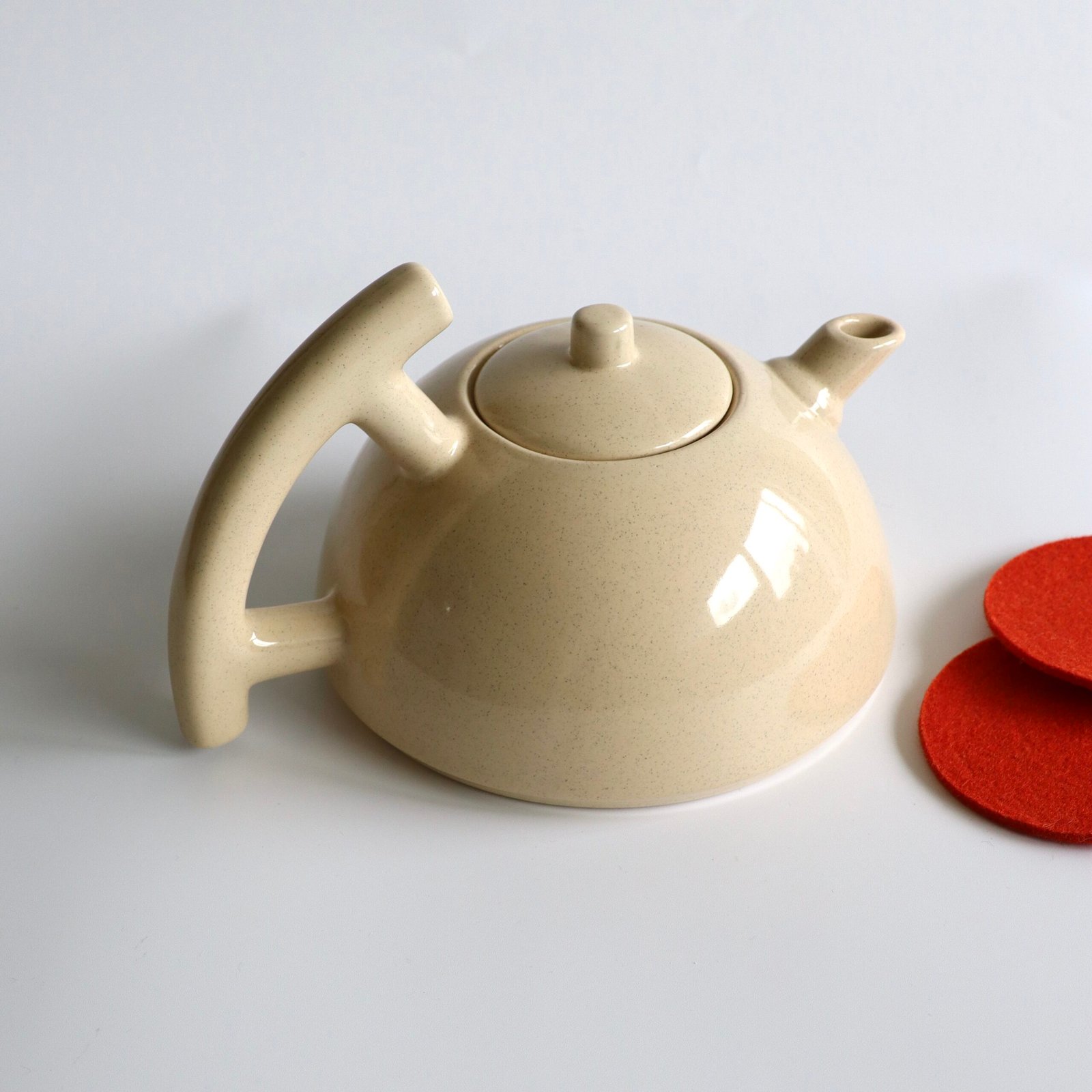 Beige keramische theepot met deksel en spikkeltjes in het glazuur, zijaanzicht.