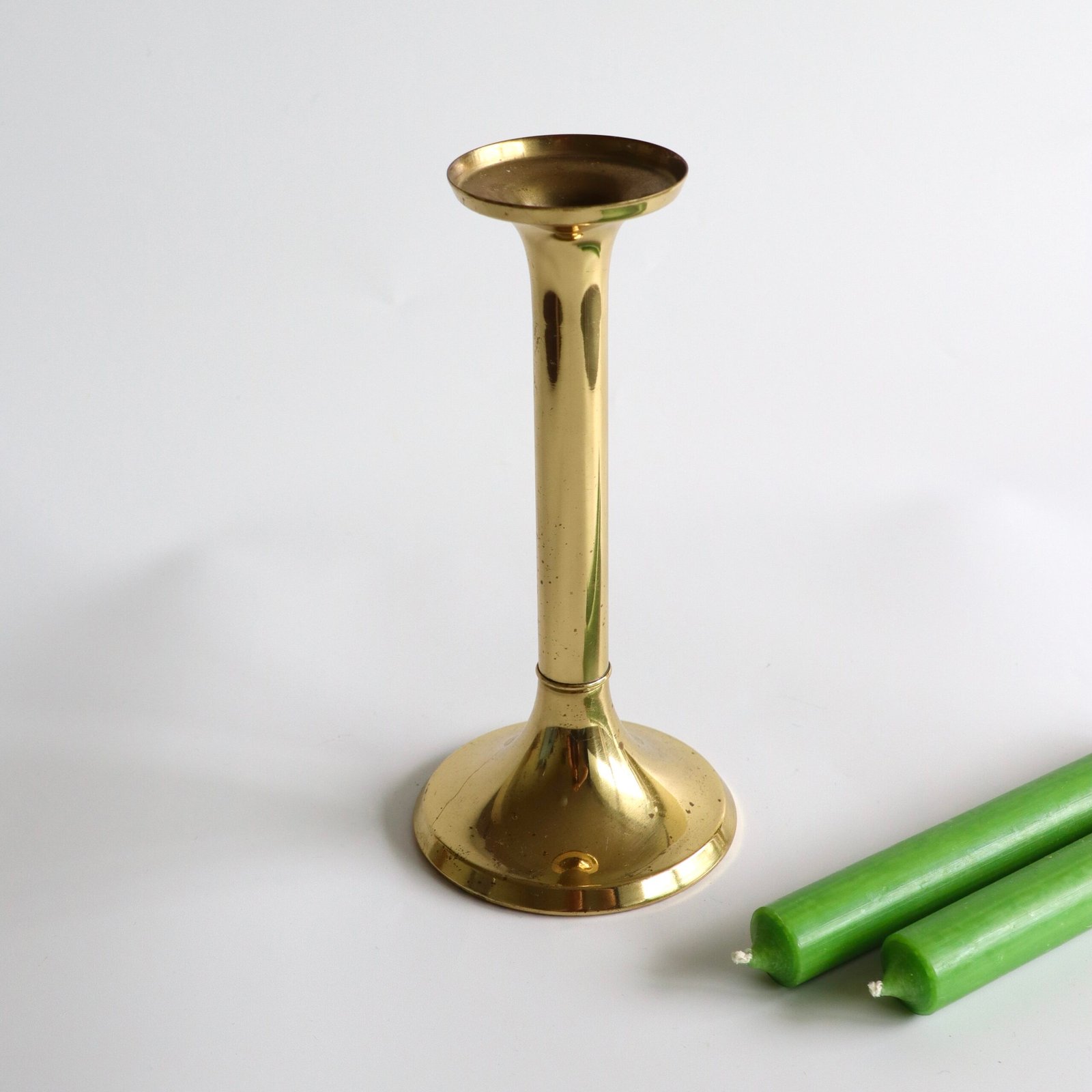 Voorkant van de vintage messing kandelaar met zichtbare oxidatievlekken op de gladde stijl.