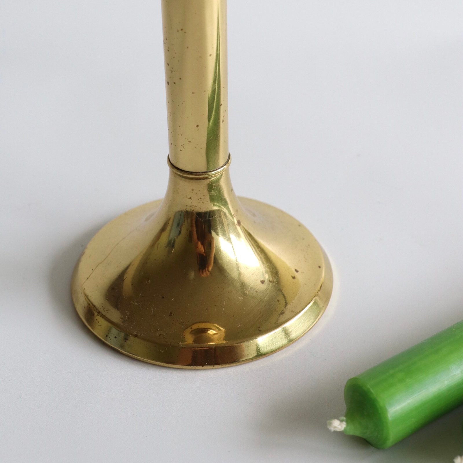 Detail van de basis en voet van de messing kandelaar, schuine weergave met oxidatiepatroon.