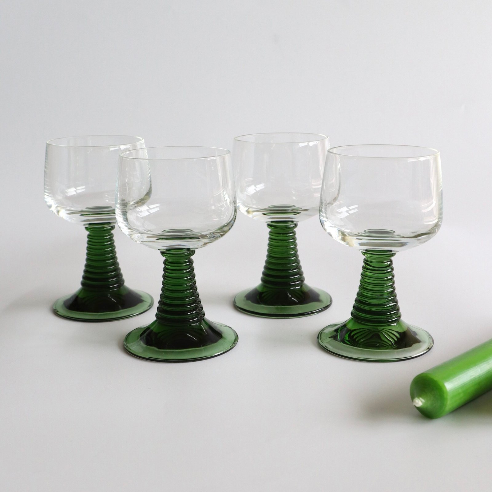 Set van vier vintage Roemer-glazen met groene geribde voet en helder glaswerk, geschikt voor aperitieven of wijn.