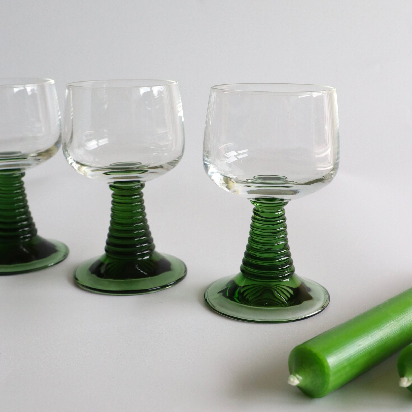 Detail van twee vintage Roemer-aperitiefglazen met groen geribbelde voet en gegroefde steeldetail.