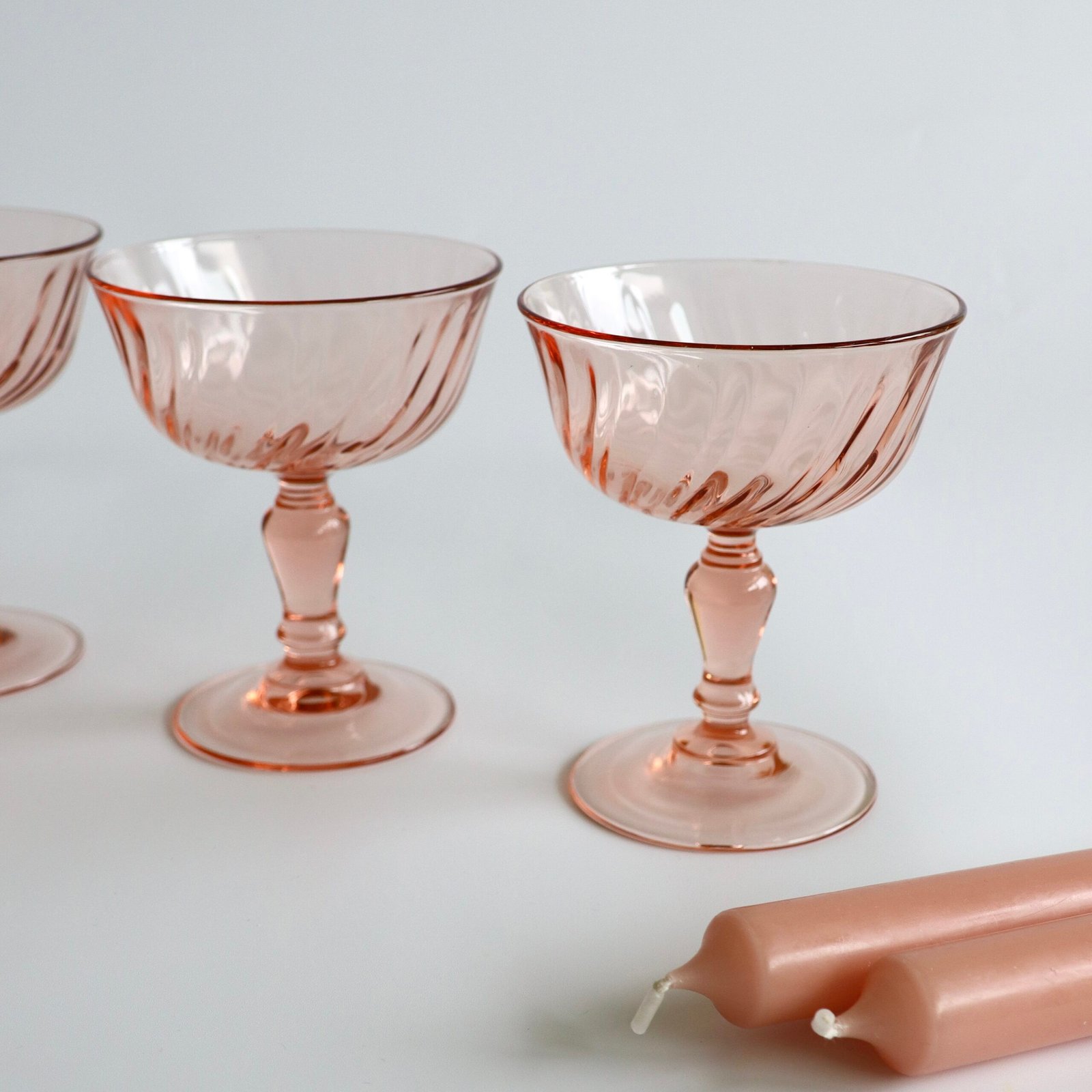 Twee roze Luminarc Rosaline champagnecoups van dichtbij, detail van het swirl-decor en voet.