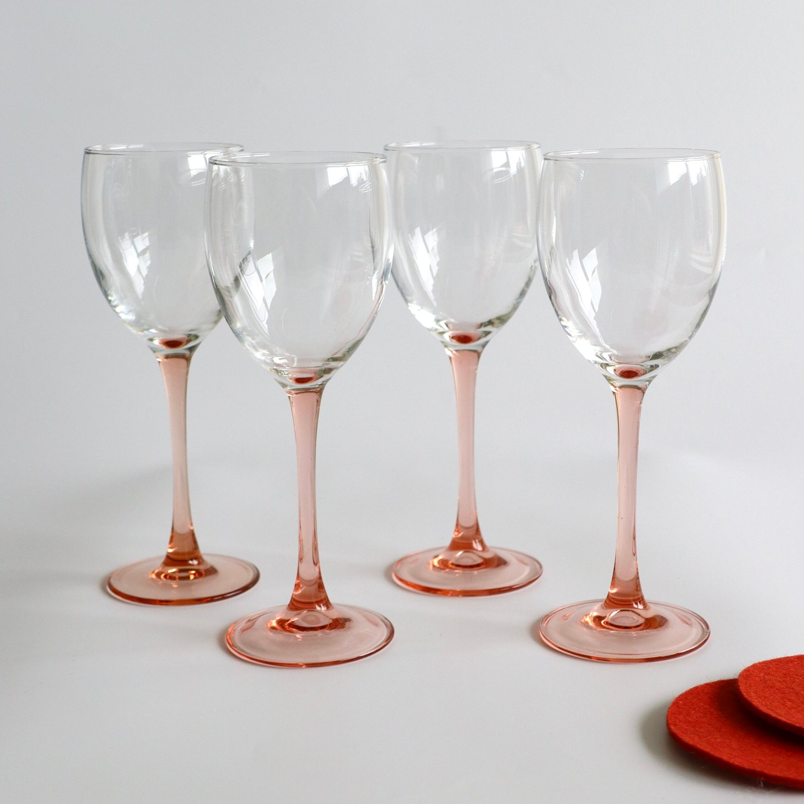 Set van vier Luminarc wijnglazen met roze glazen voet en stengel, helder glas bovenkant.