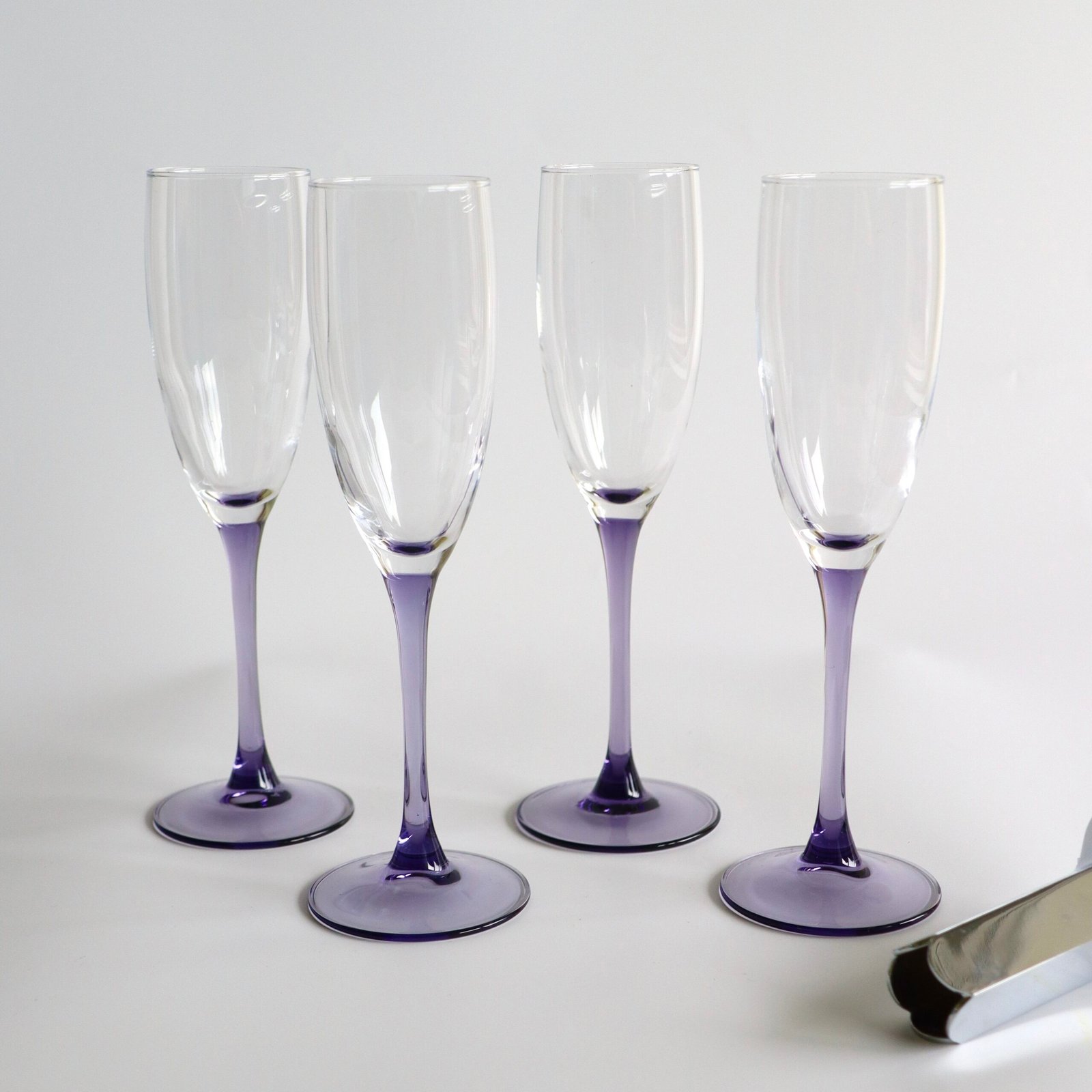 Set van vier Luminarc champagneglazen met lila gekleurde voet en stengel, helder glas.