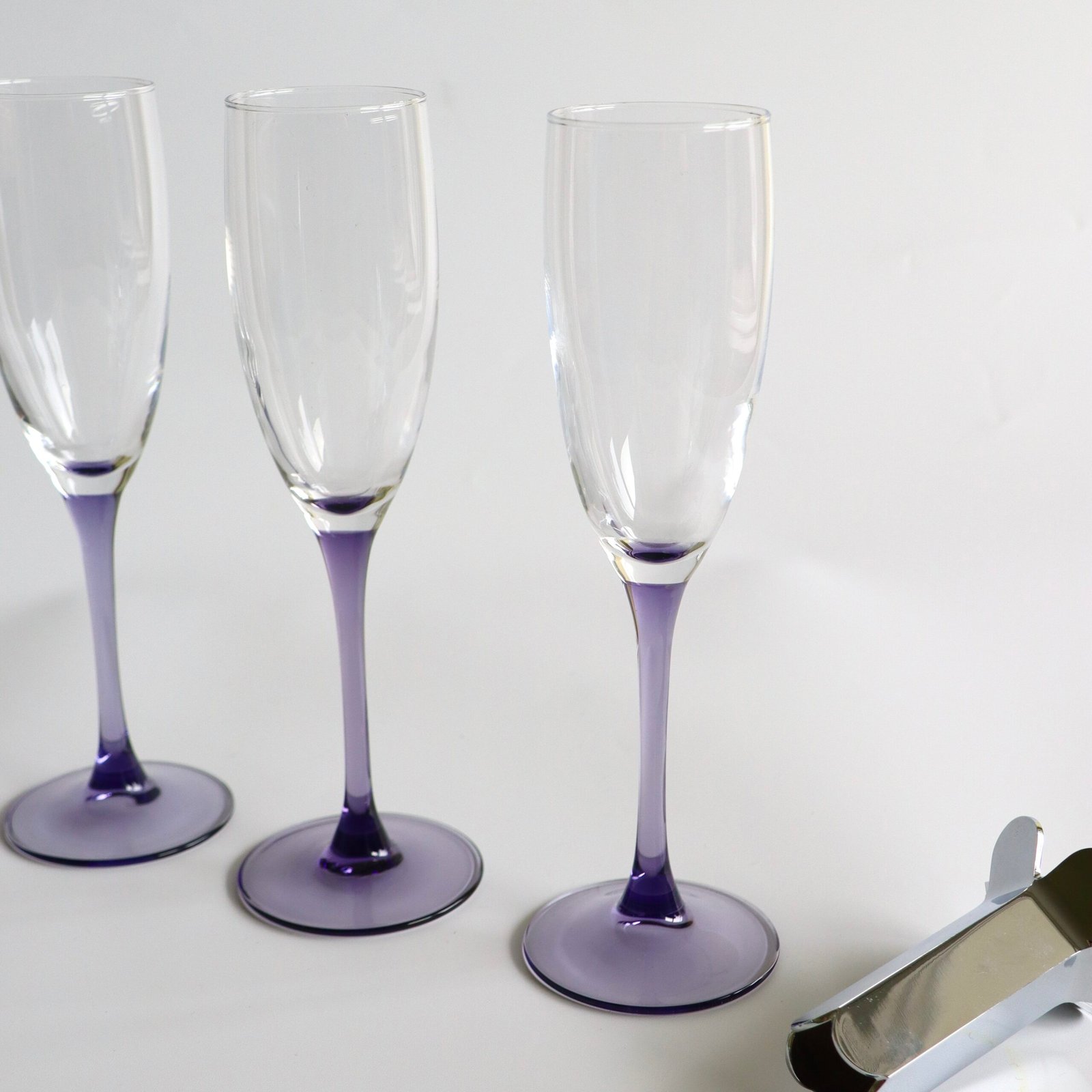 Drie Luminarc France champagnefluutes uit de Lilac-lijn met paarse voet en transparante stengel in detail weergegeven.